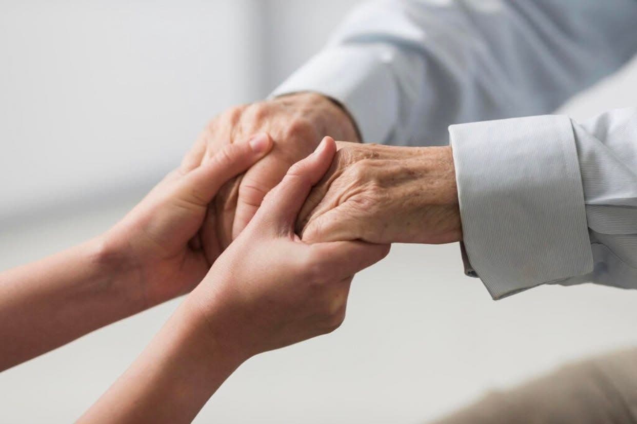 A younger person's hands holding an elderly person's hands